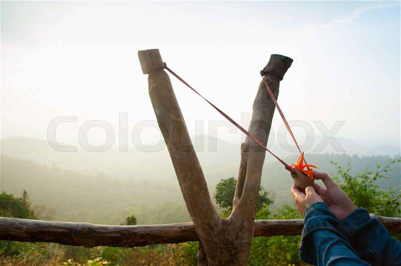Hand pulling sling shot preparing to shot the tree seed into the forest, stock photo