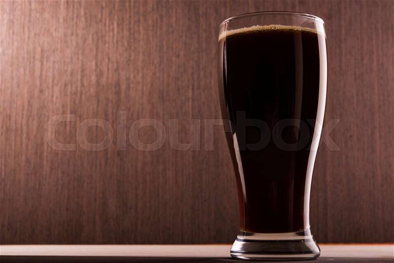 Dark beer into glass on a old background, stock photo