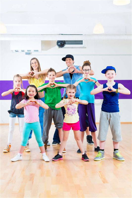 Dance teacher giving children Zumba fitness class in gym, stock photo