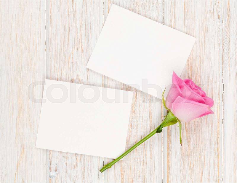 Blank photo frames and pink rose over wooden table. Top view with copy space, stock photo