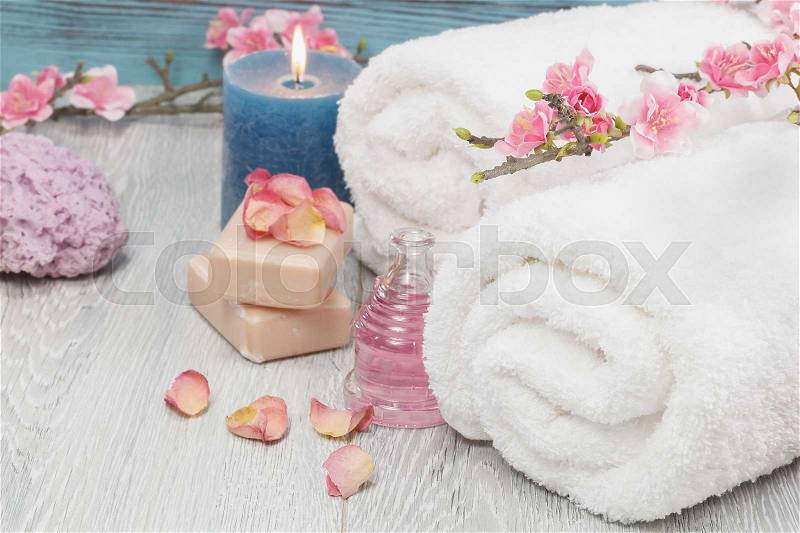 Spa and wellness setting with rose petals, natural soap, candle and towel, stock photo