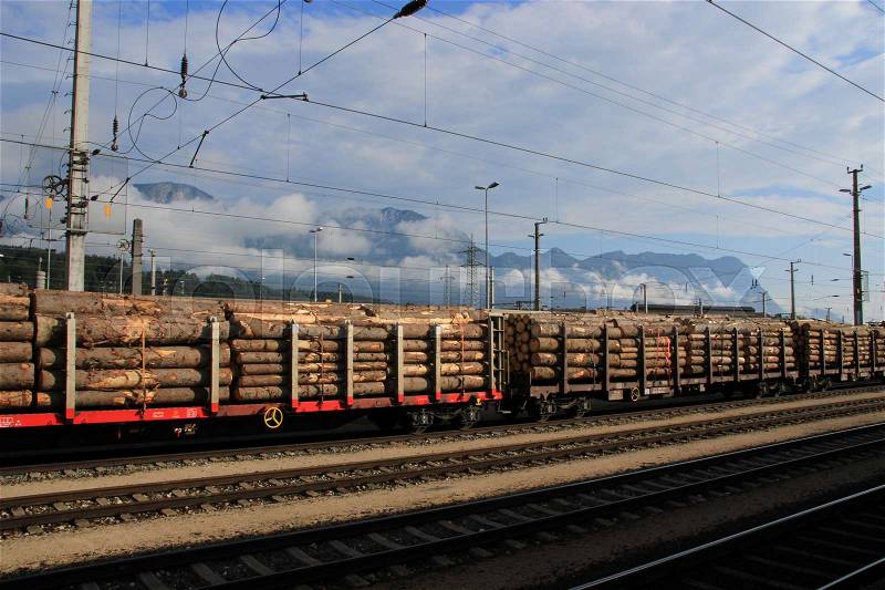 Trunks of trees wait on the train station in Wörgl in Austria for transport in the summer, stock photo