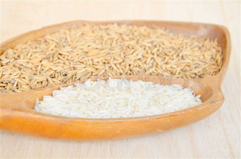 Different of paddy and raw rice in wooden bowl on wooden background, stock photo