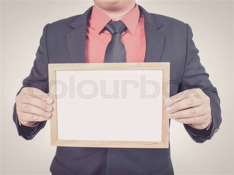 Businessman standing and holding white board with copy space, stock photo
