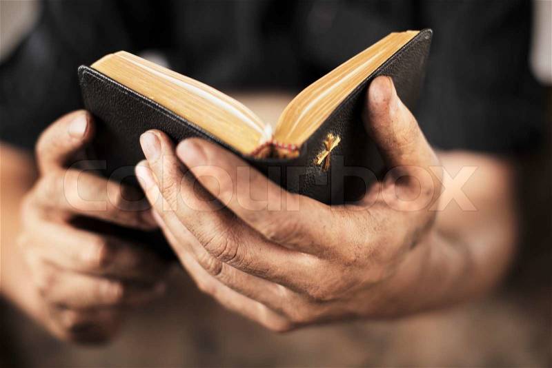 Dirty hands holding an old bible. Very short depth-of-field, stock photo