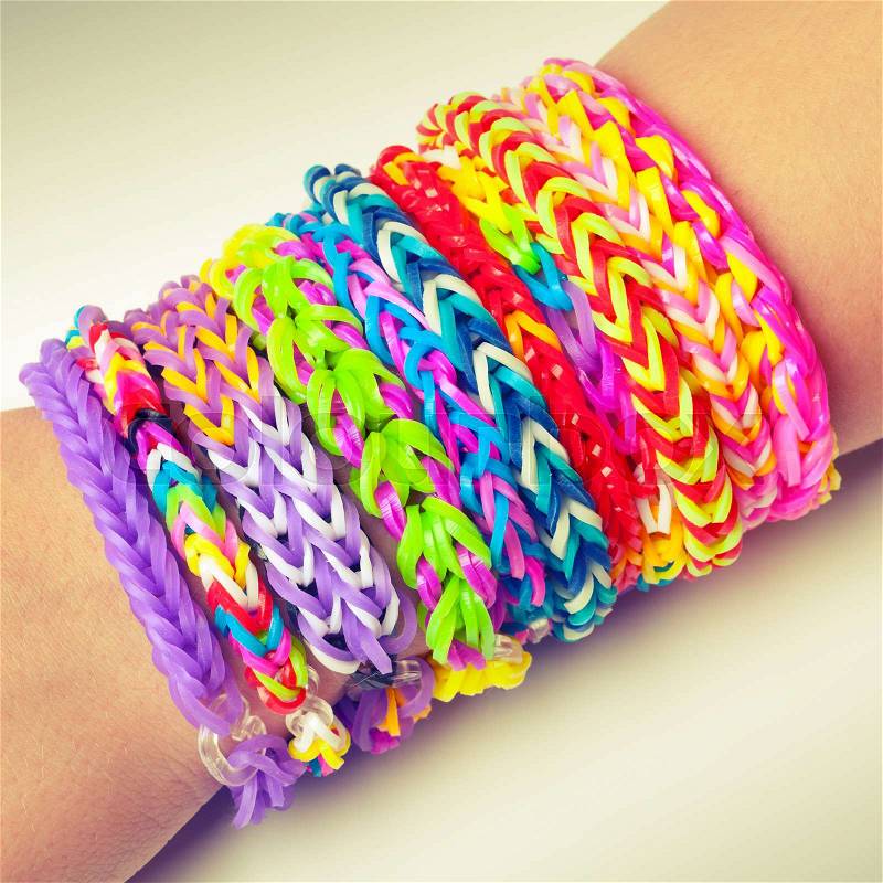 Colorful rubber rainbow loom band bracelets on wrist, trendy kids fashion accessories. Vintage retro tonal photo filter correction, stock photo
