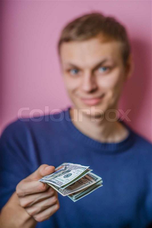 A young man close-up , gives or takes money. Dollars. Holds money in hands. . Photos, stock photo