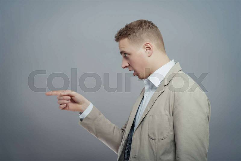 Closeup side view portrait of young man, laughing, pointing with finger at someone or something. Positive human face expressions, emotions, feelings, attitude, approach, stock photo