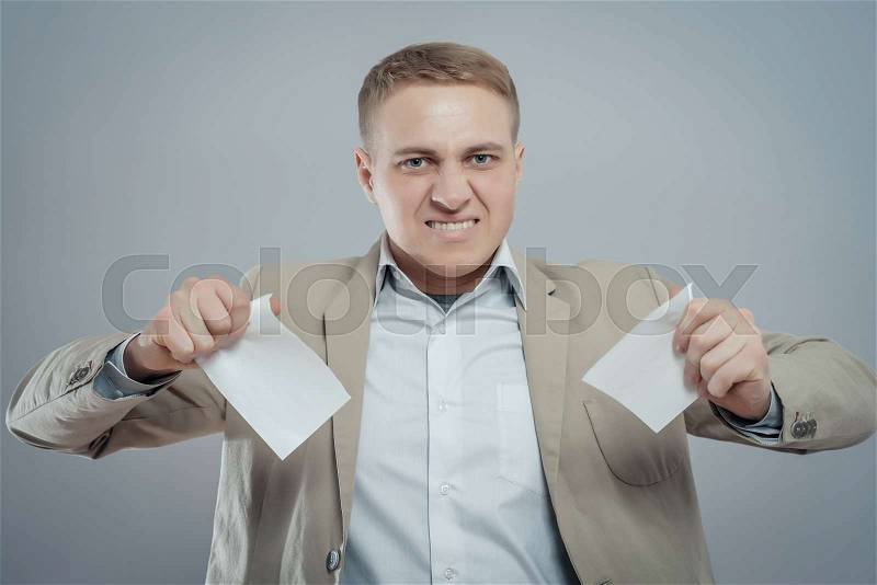 A picture of an angry businessman tearing documents, stock photo