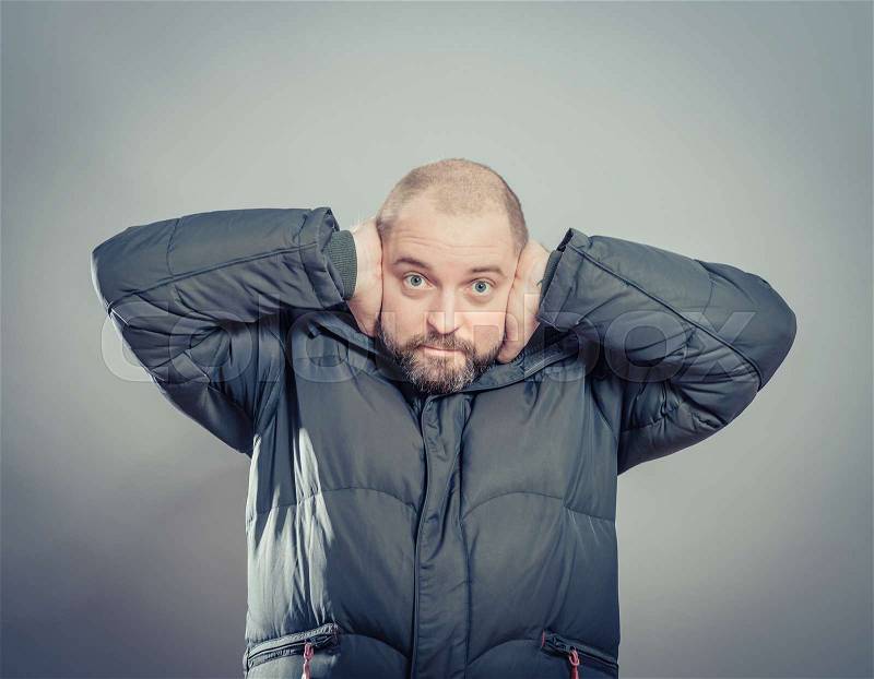 Annoyed man covering his ears with his hands, stock photo