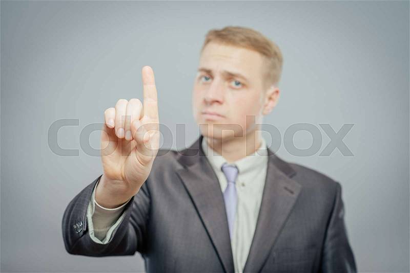 Closeup portrait of young business man pointing up having idea, solution, showing with index finger number one, isolated on gray background. Positive human emotions, facial expressions, symbols, sign, stock photo