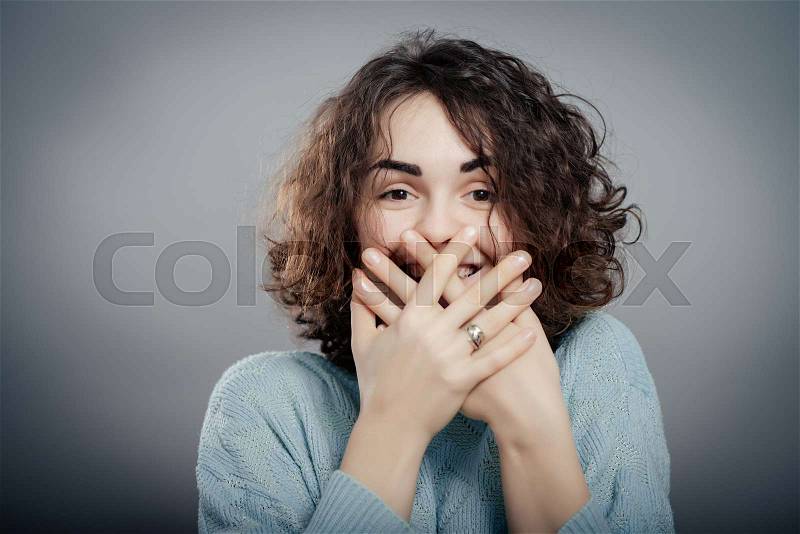 Woman giggles covering her mouth with hand, stock photo