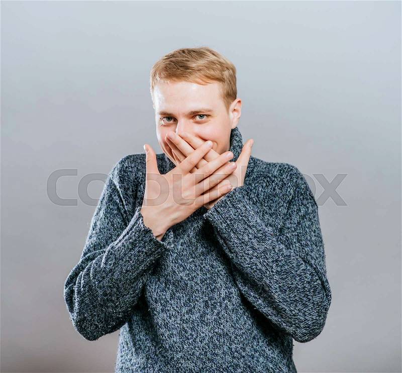 Man covers his mouth with his hands, fear, does not want to roar, laughing, stock photo