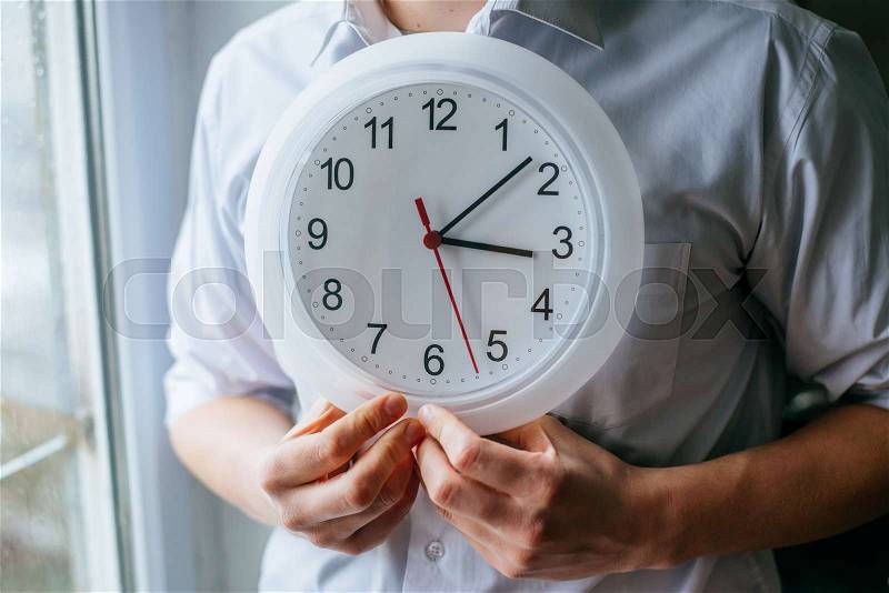 Man holding a clock in the office, stock photo