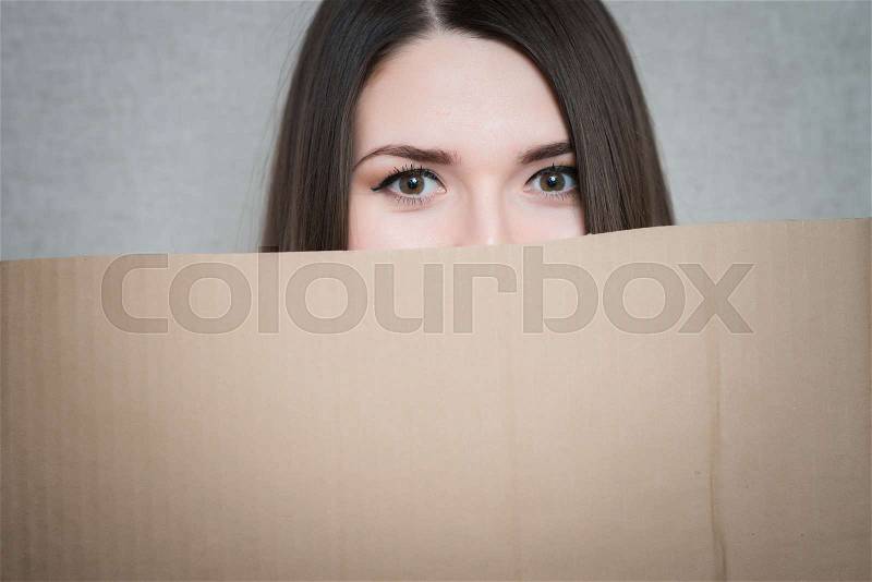 Banner sign woman peeking over edge of blank empty paper billboard with copy space for text. Beautiful Asian Caucasian woman looking surprised and scared - funny. , stock photo
