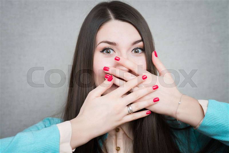 Young pretty woman holding hands over her mouth over grey background, stock photo