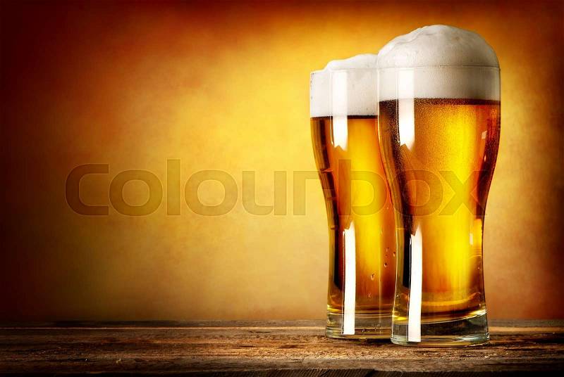 Two glasses of lager on a wooden table, stock photo