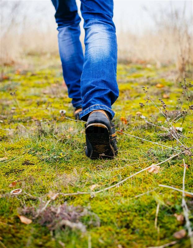 Person wearing walking shoes takes a step on a mountain hiking path, closeup photo, stock photo