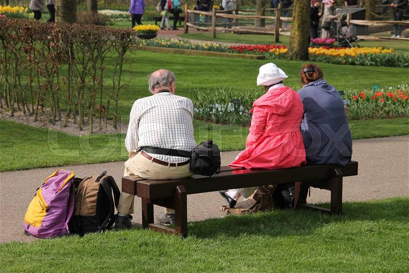 Parents with daughter sit on a bench and have a break in the Garden of Europe, called Keukenhof, in Lisse in spring, stock photo