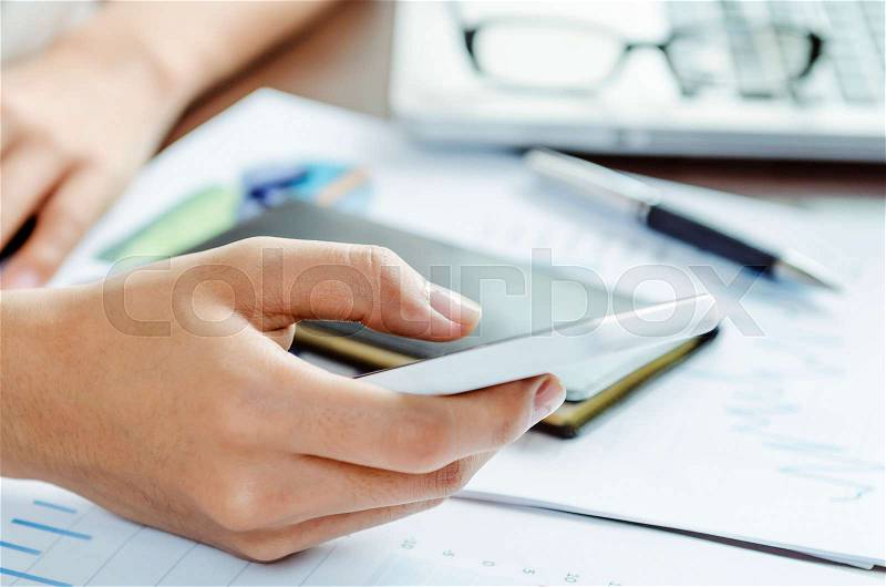 Woman using her smart phone in an office, stock photo