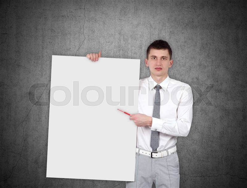 Businessman holding blank placard on gray wall background, stock photo