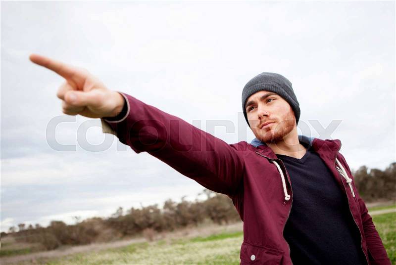 Cool handsome guy with beard at outside pointing something, stock photo