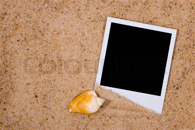 Photo frame with sea shells on sand background, stock photo