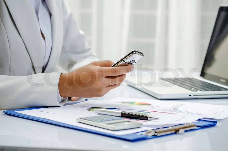 Businesswoman making text message by mobile phone, stock photo
