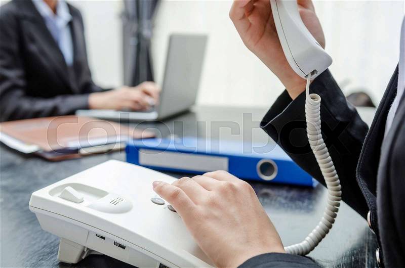 Business person making a call and another working on PC, stock photo