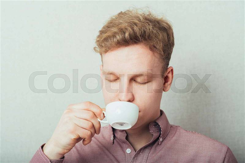 Man drinks coffee from a small white cup of coffee, stock photo