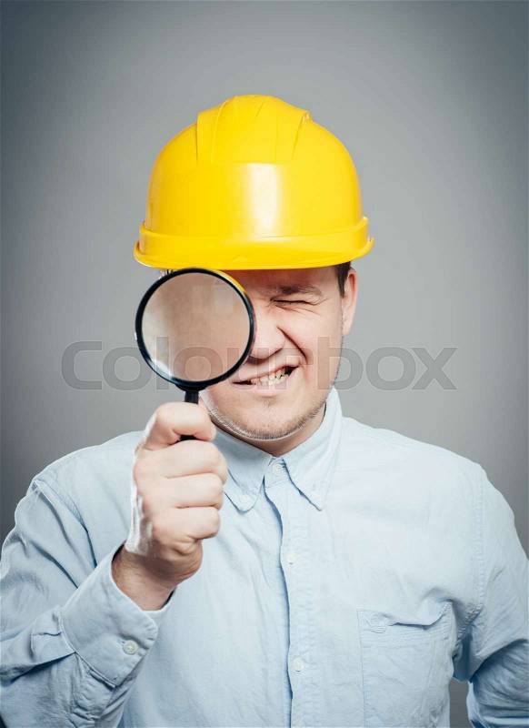 Asian engineer man wear hardhat hold a magnifying glass focus on the glass isolated , stock photo
