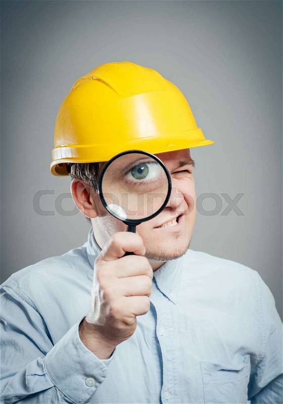 Asian engineer man wear hardhat hold a magnifying glass focus on the glass isolated , stock photo