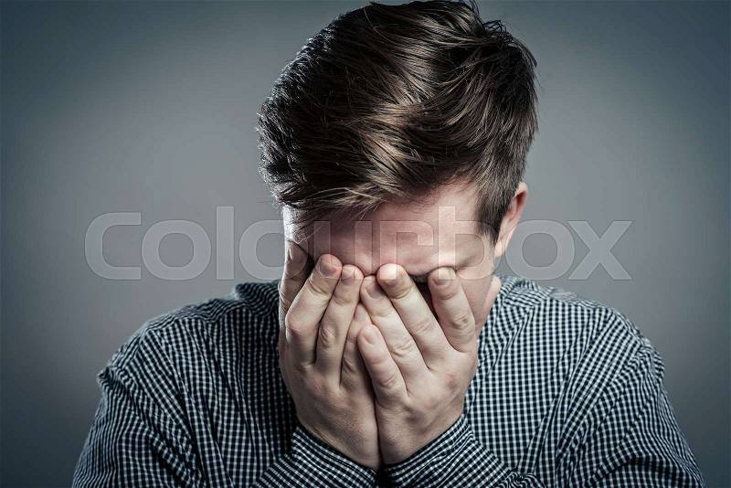 Portrait of a young man with his hand on his eyes, stock photo