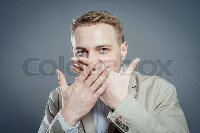 Closeup portrait of young business man closing mouth with hand, shocked, disgusted by what someone said, what he saw, isolated on white background. Negative human emotion, facial expression, feelings, stock photo
