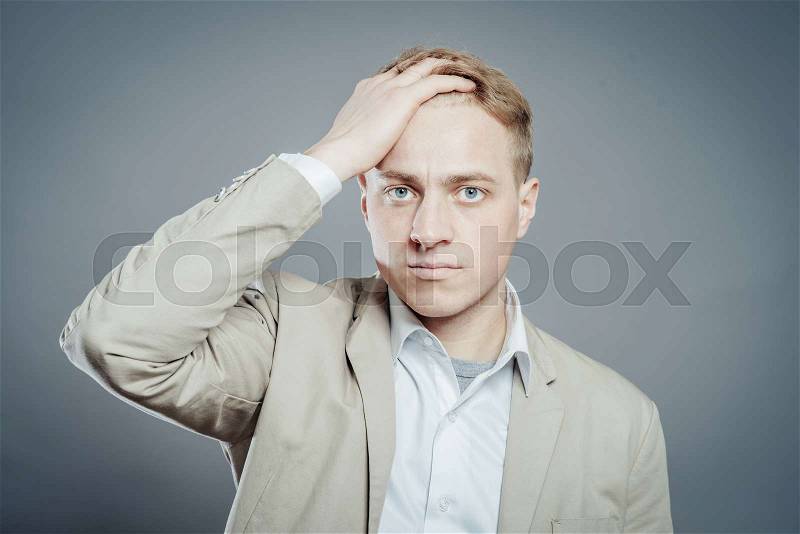 Closeup portrait of angry, frustrated man, hand on head. Negative human emotions and facial expressions, stock photo