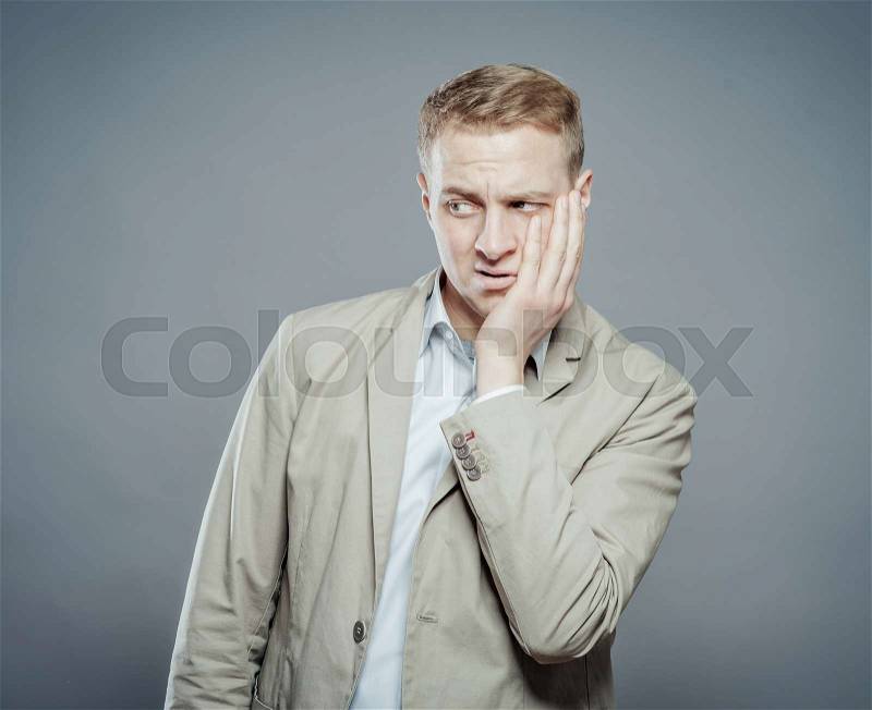 Young businessman with teethache and frustration in business suit, stock photo