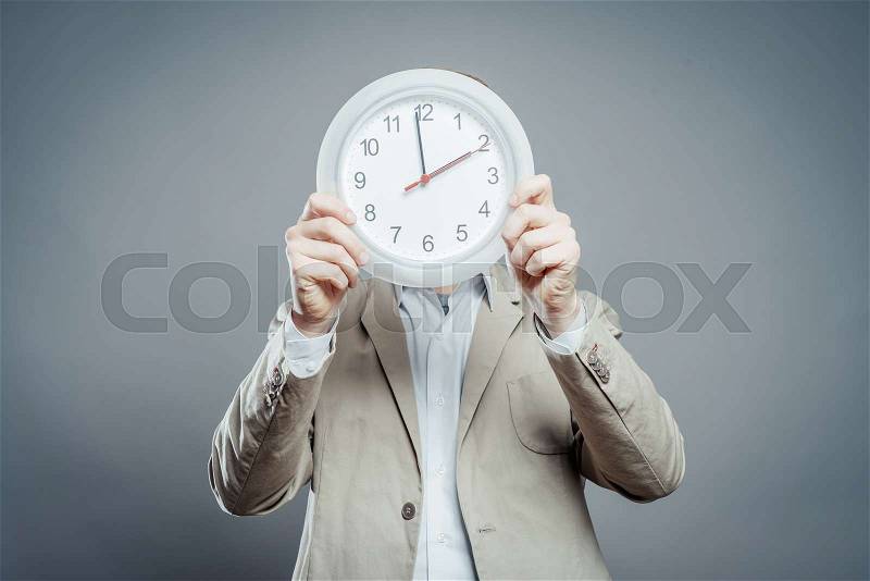 Man covering his face with wall clock, stock photo