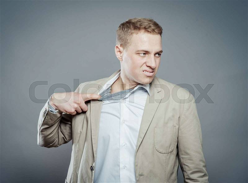 Closeup portrait of young man opening shirt to vent,it\'s hot. Negative emotion, facial expression, feeling, stock photo