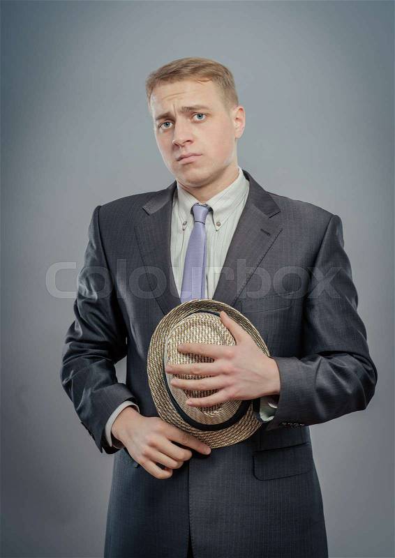 Young man in suit is holding a straw hat, stock photo