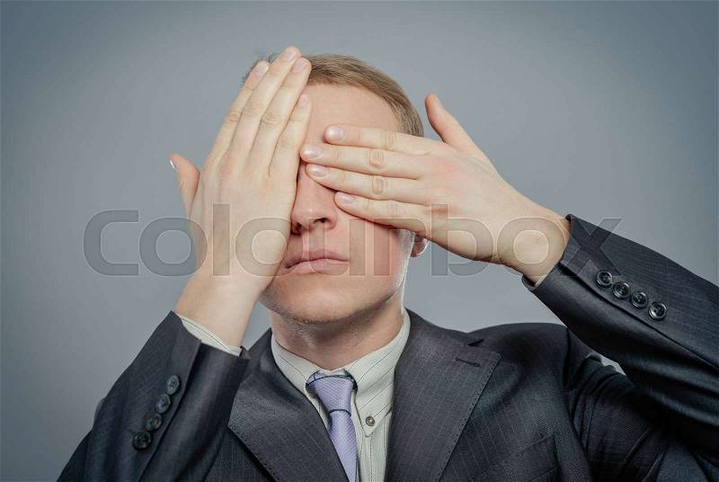 Portrait of a young man covering his eyes with hands, stock photo