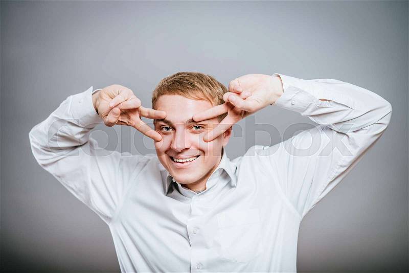 Young casual man on eyes showing victory sign while holding a hand in his pocket, stock photo