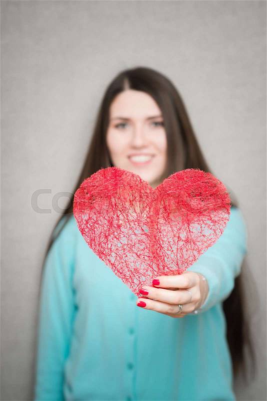 Young happy woman hold Love symbol red heart. Isolated on studio background female model, stock photo