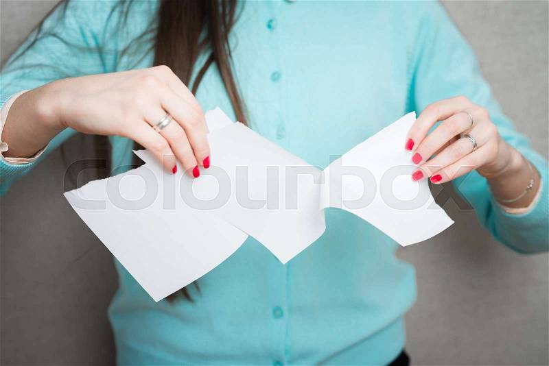 Breaking contract. Furious young woman tearing up paper , stock photo
