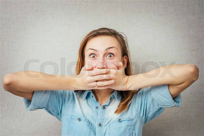 A shocked and frightened woman covering her mouth in surprise and disbelief. Isolated, stock photo