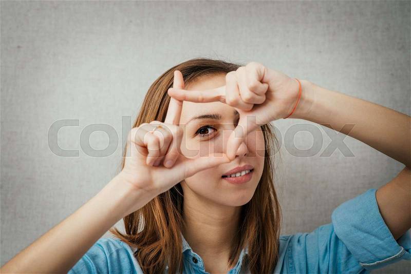 Woman making a frame out of hand. isolated on gray background, stock photo