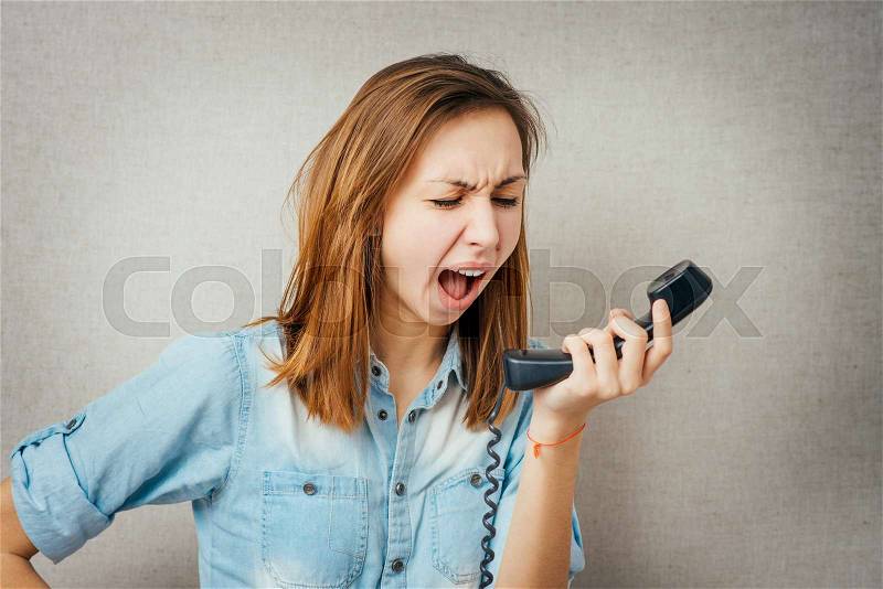 Woman talking on the phone, angry shouts into the phone. isolated on gray background, stock photo