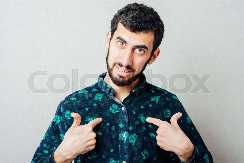 Handsome young bearded man gesturing to himself as if to say ; who me?, stock photo