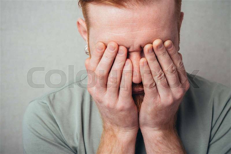Young hipster red bearded Man closes his eyes with his hands, stock photo