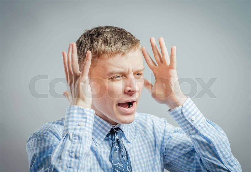 Furious young men holding his head in hands and screaming, stock photo