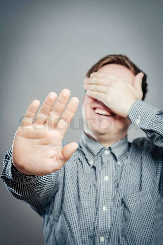 Young man laughing covering his face, stock photo